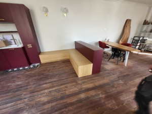 Photo de galerie - Fabrication d'une banquette en chêne vernis avec un meuble laqué bordeaux servant d'assise à la banquette.