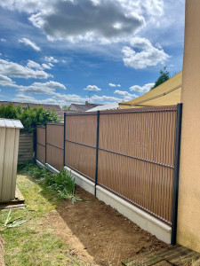 Photo de galerie - Installation d’un grillage rigide avec soubassement béton et lames occultante pvc imitation bois