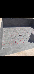 Photo de galerie - Pose de carrelage pour piscine avec carreaux grand format et système de nivellement pour garantir une surface parfaitement plane. Réalisation des découpes, alignements et finitions pour un rendu propre, esthétique et durable.