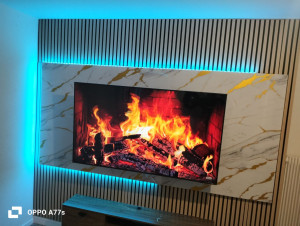 Photo de galerie - Installation et habillage d'un mur TV avec panneaux décoratifs, effet marbre et éclairage LED.
