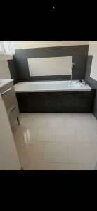 Photo de galerie - Rénovation complète salle de bain : carrelage grand format au sol, habillage baignoire et murs en grès cérame gris anthracite.