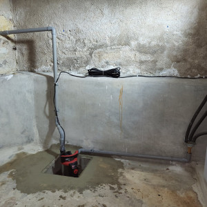 Photo de galerie - Installation d'une pompe de relevage d'eaux pluviales dans une cave, canalisations intérieures et extérieures enterrées pour raccordement au réseau existant.