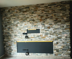 Photo de galerie - Mur de salon en pierre de parement avec réservation de support tv et meuble tv suspendu 