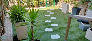 Photo de galerie - Réalisation d'un jardin avec gazon synthétique cailloux de décoration et géotextile.