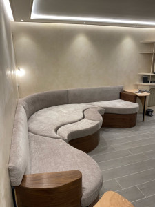 Photo de galerie - Banquette sur mesure avec formes arrondies, structure en bois, habillage, assises et dossiers rembourrés. Fabrication et pose entièrement réalisées sur mesure.