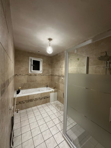 Photo de galerie - Salle de bain en cours de finition avec pose des éléments baignoire avec tablier en placo et trappe 40/40 + tablette,receveur et paroi de douche + robinetterie, faïence imitation travertin + frise (carrelage au sol d’origine)