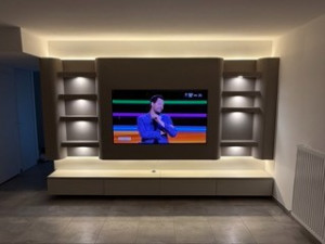 Photo de galerie - Meuble TV entièrement réalisé sur mesure, avec niches éclairées, lignes courbes et LED intégrées pour un rendu moderne et élégant.
Un design épuré qui structure la pièce et met la télévision en valeur avec une ambiance lumineuse haut de gamme.