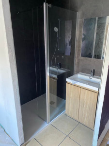 Photo de galerie - Création d’une salle de bain dans une pièce qui n’en possédait pas initialement, tout en conservant l’existant. Installation d’un meuble vasque et intégration d’un bac à douche encastré dans le sol avec pose d’une paroi de douche. Aménagement réalisé en i