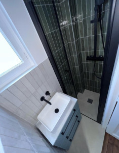 Photo de galerie - énovation complète d'une salle de bain moderne avec douche à l'italienne, carrelage grand format et meuble vasque suspendu.