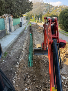 Photo de galerie - Réalisation d’une tranchée pour réseau fibre optique avec pose de fourreaux télécom, grillage avertisseur et préparation du remblaiement. Intervention réalisée à la mini-pelle.