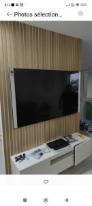 Photo de galerie - Mur en tasseaux de bois,avec découpes autour du meuble TV et support TV.
