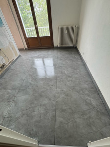 Photo de galerie - Réalisation d’un sol intérieur en carrelage grand format 100x100 cm effet pierre. La pose soignée, les joints fins et l’alignement précis des carreaux offrent un rendu moderne, élégant et lumineux.