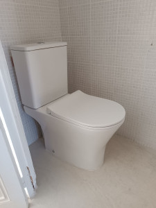 Photo de galerie - Pose d’un WC moderne avec raccordement à l’alimentation et à l’évacuation. Installation soignée, mise en service et vérification de l’étanchéité pour une finition propre et durable.