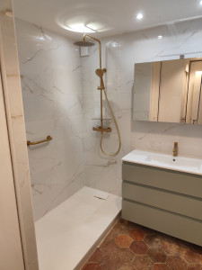 Photo de galerie - Réalisation d'une salle de bain faïence imitation marbre avec nervure doré et robinetterie doré plus pose de meubles suspendu et miroir.