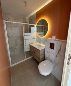 Photo de galerie - Réalisation complète d’une salle de bain contemporaine avec douche à l’italienne, meuble suspendu en bois clair et WC encastré.