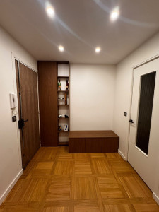 Photo de galerie - Meuble sur mesure : un placard pour cacher le tableau électrique, suivi d'un meuble étagère et d'un banc de rangement pour les chaussures en mélamine noyer. La porte d'entrée du logement a été replaque avec une feuille de placage en bois noyer pour h