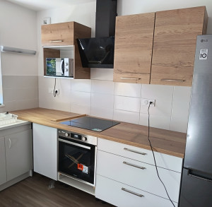 Photo de galerie - Installation des meubles bas et hauts ainsi que de la hotte,du four et de la plaque avec une découpe du plan de travail pour cette dernière 
un trou a été effectué sur le côté du meuble du micro-onde pour le passage de la prise 
