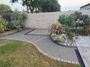 Photo de galerie - Réalisation d'une dalle en béton armé pour abri de jardin, avec pose de caniveau et création d'une allée en béton désactivé avec sa chaînette de pavés.