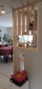 Photo de galerie - Création d'une clostra en bois pour séparer l'entrée de la cuisine tout en laissant passer la lumière et servant d'élément de décoration 