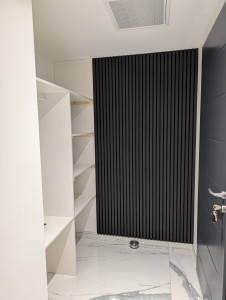 Photo de galerie - Réalisation complète du meuble sur mesure et installation d’un parement mural en tasseaux noirs pour apporter une touche moderne et chaleureuse à la pièce.