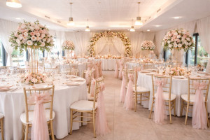 Photo de galerie - Salle de réception élégante avec décoration florale, tables rondes, chaises dorées et ambiance raffinée pour mariages, anniversaires et événements privés