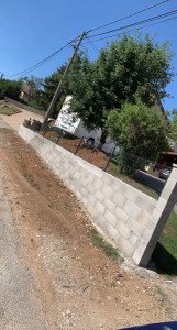 Photo de galerie - Mur de clôture en parpaings monté et aligné, avec pose de poteaux et grillage rigide.