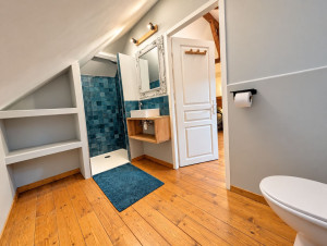 Photo de galerie - La rénovation et réagencement d’une salle de bain sous combles : douche carrelée, meuble vasque bois sur mesure, niches intégrées en plaque de plâtre sous rampant et parquet massif rénové.