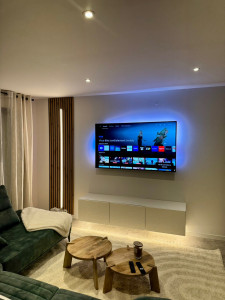 Photo de galerie - Salon : Mise en place de bande LED sur panneau mural et sous meuble télé.