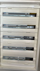 Photo de galerie - Tableau électrique en cours de montage et d’organisation. Répartition des circuits, protections et vérifications réalisées sur place. Contrôle du bon fonctionnement et préparation pour une installation fiable et sécurisée.