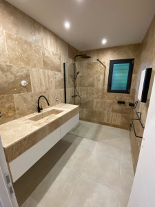 Photo de galerie - Réalisation d’une salle de bain complète : chape douche à l’italienne avec caniveaux , pose carrelage 60x60 au sol , pose travertin 60x40 au mur , installation meuble vasque / paroi de douche et accessoires 