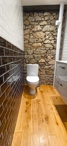 Photo de galerie - Toilette  + parquet massif collé + meuble + vasque + mur pierres apparentes + carrelage