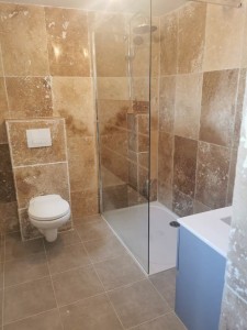Photo de galerie - Petite salle d’eau de 5m2 refaite en travertin avec pose wc suspendu et bac à douche, avec la plomberie, l’électricité , le carrelage au sol et la pose du meuble. 