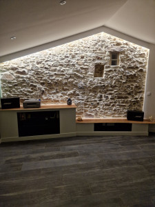 Photo de galerie - Petit amusement en pierre apparente jointée, meuble Hi-Fi et TV en placo avec tablette en bois sapelli (bois exotique) et c'est étagères en verre trempé    