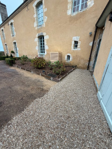 Photo de galerie - Aménagement d’une cour avec réalisation d’allées en gravillons pour un rendu propre et esthétique. Création et délimitation des massifs paysagers à l’aide de bordures pour structurer les espaces et mettre en valeur les plantations.