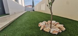 Photo de galerie - - Mise en place du gazon synthétique avec délimitation des plantation par pose de pierre de Montpins