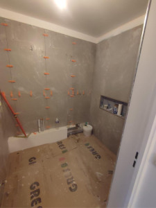 Photo de galerie - Pose de carrelage mural grand format avec alignement précis et joints réguliers.