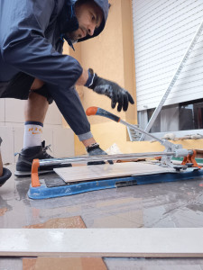 Photo de galerie - Travail minutieux de découpe du carrelage à la carrelette, pour une finition nette et soignée.