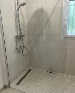 Photo de galerie - Réalisation TD Plomberie à Écommoy, installation d’une douche à l’italienne moderne avec robinetterie murale chromée et carrelage effet pierre beige.