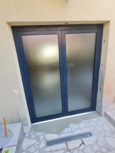 Photo de galerie - Pose de porte en aluminium : installation complète, réglages, ajustements et finitions. Travail soigné pour un résultat solide, propre et parfaitement aligné.
