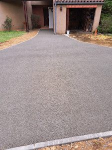Photo de galerie - Réalisation d’une allée en béton drainant gris, avec une finition soignée. Un revêtement perméable qui facilite l’infiltration des eaux de pluie et limite la formation de flaques.