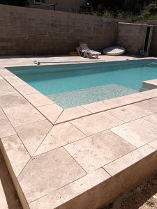 Photo de galerie - Pose de margelles et carreaux en travertin autour d'une piscine