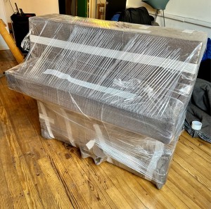 Photo de galerie - Déménagement d’un piano avec couverture et film de protection.