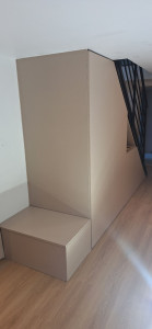 Photo de galerie - Fabrication et installation d’un dressing en bois sur mesure sous l’escalier, adapté à la forme de l’espace.