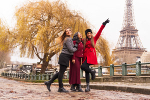 Photo de galerie - Trois amies partagent un moment de bonheur au bord de la Seine, avec la Tour Eiffel et un saule majestueux en arrière-plan, célébrant l'amitié et la vie