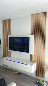 Photo de galerie - Installation de meubles suspendus avec bande LED à l'intérieur et éclairage encastré et téléviseur suspendu au mur