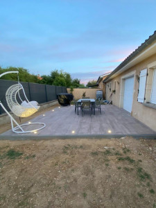 Photo de galerie - Création d'une terrasse en dalle céramique grand format, agrémentée de spots lumineux encastrés pour une ambiance en soirée. Un espace détente et repas entièrement aménagé, avec finitions soignées en bordure.