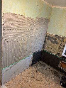 Photo de galerie - État initial du chantier : murs très irréguliers et abîmés, nécessitant une importante préparation du support avant la pose du carrelage.