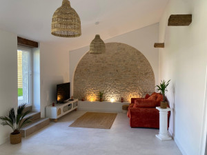 Photo de galerie - Plaquiste 17 – Travaux de placo, peinture et rénovation intérieure en Charente-Maritime. Réalisation d’un salon moderne avec finitions soignées, peinture décorative, mur en pierre apparente et éclairage d’ambiance. Devis gratuit au 06 60 24 07 13.