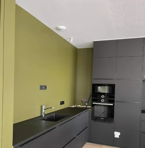 Photo de galerie - Peinture d'une cuisine (vert olive). Finition premium avec un rendu parfaitement lisse. Le travail est très propre, avec des lignes parfaites entre le plafond et les meubles.