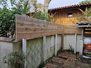 Photo de galerie - Pose de planches en bois pour faire un brise-vue.